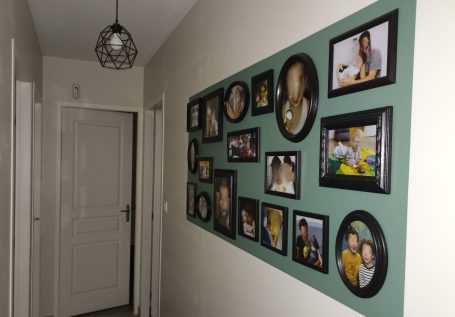 Sur un fond vert menthe, cette accumulation de photos personnelles invite à l'intimité dans le couloir des chambres