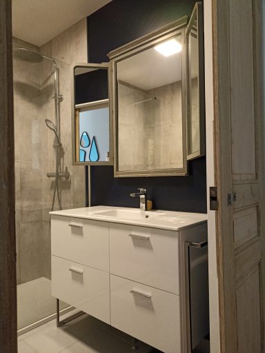 Mix d'un meuble vasque en céramique offrant rangements et plan de travail, avec un miroir triptyque ancien qui agrandit l'espace.