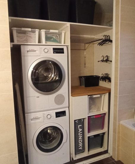 Les portes miroirs coulissent derrière la tête de baignoire: électroménager, bacs à linge sale, étendoir et bacs de rangement apparaissent.