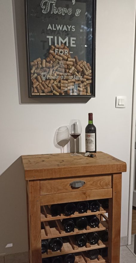 Ancien meuble de métier muni d'étagères à bouteilles, surmonté d'une vitrine à bouchons, pour créer une cave à vin originale 