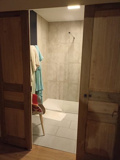 Deux portes anciennes sont montées sur rail pour permettre une ouverture grandiose sur la salle d'eau privative.